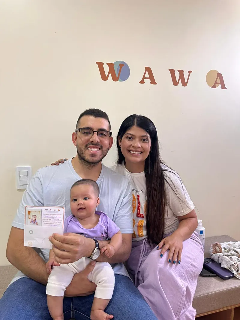 Mamá y papá con su bebé en brazos, sosteniendo su diploma de Wawa