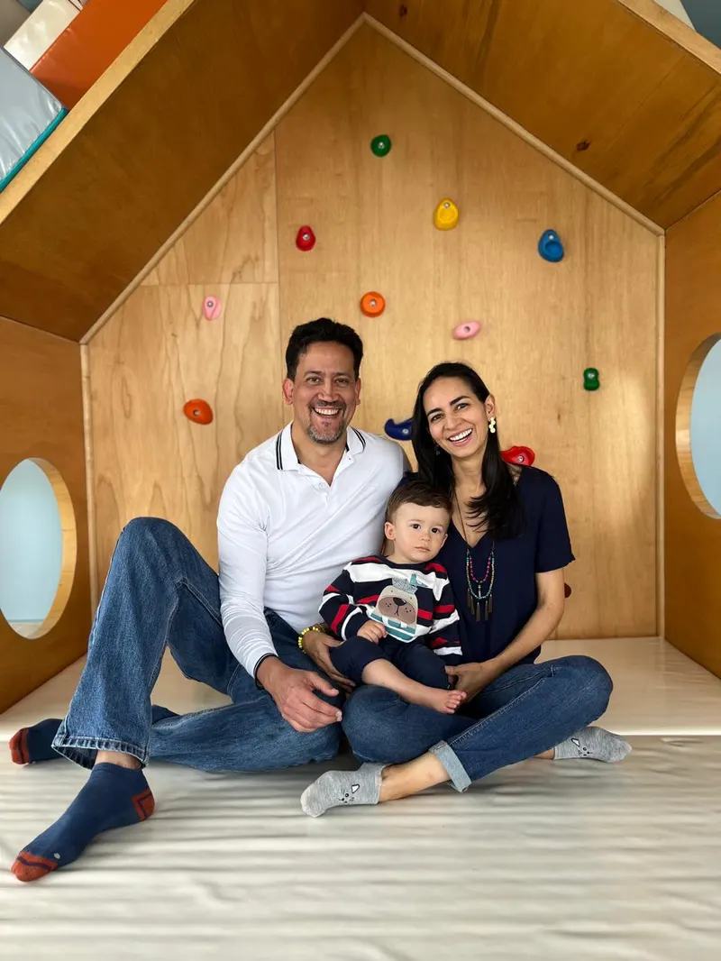 Familia sentada con su bebé dentro de la casita de madera del aula
