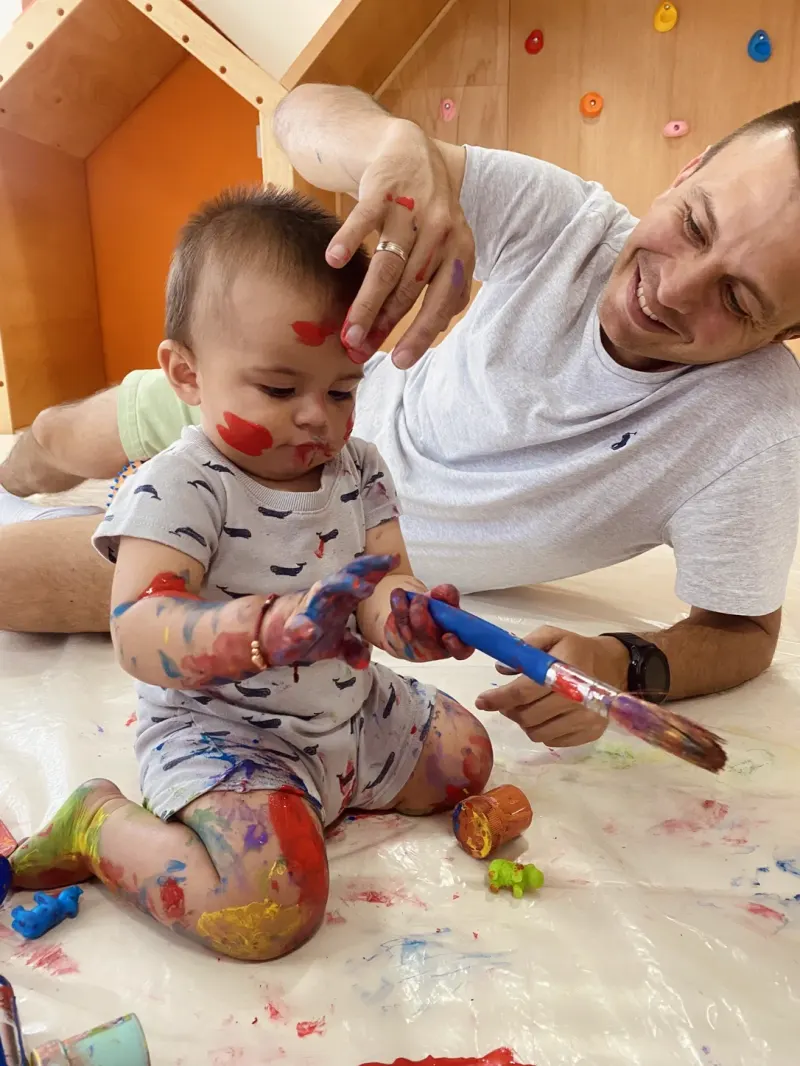 Papá tumbado en el suelo jugando con su bebé mientras pintan juntos