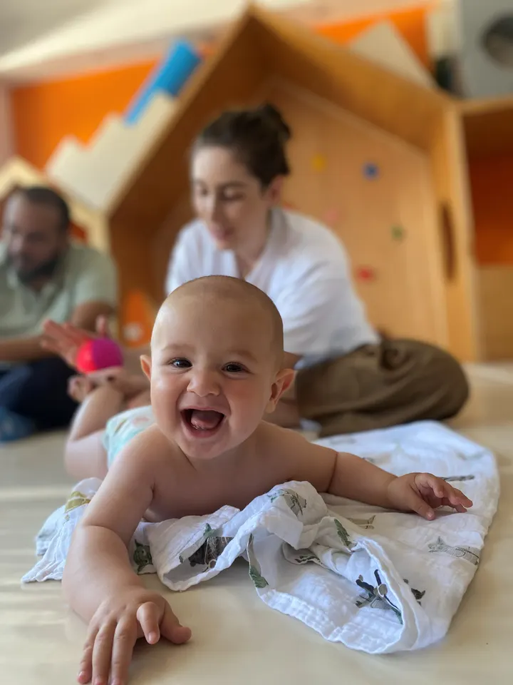 Bebé boca abajo, sonriendo, sobre una muselina en el aula de Wawa