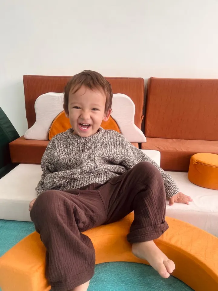 Niño sentado y riendo sobre los cojines del aula