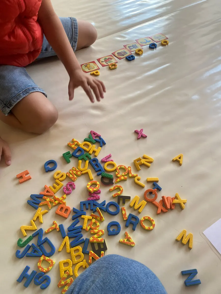Niño jugando en el suelo con letras de espuma de colores