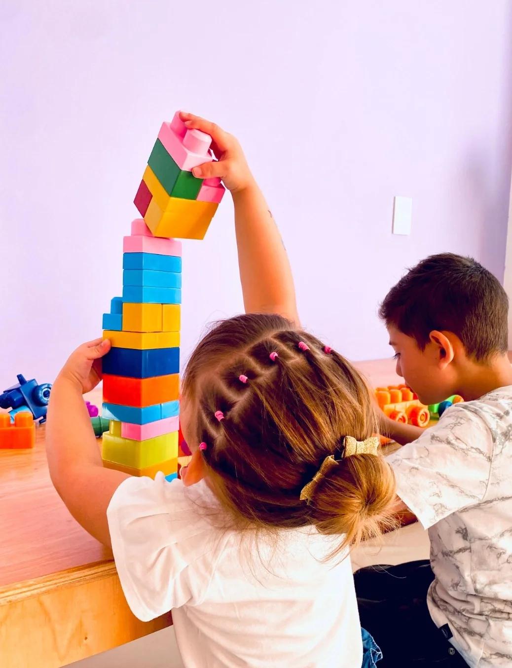 Dos niños construyendo juntos una torre alta de bloques de colores